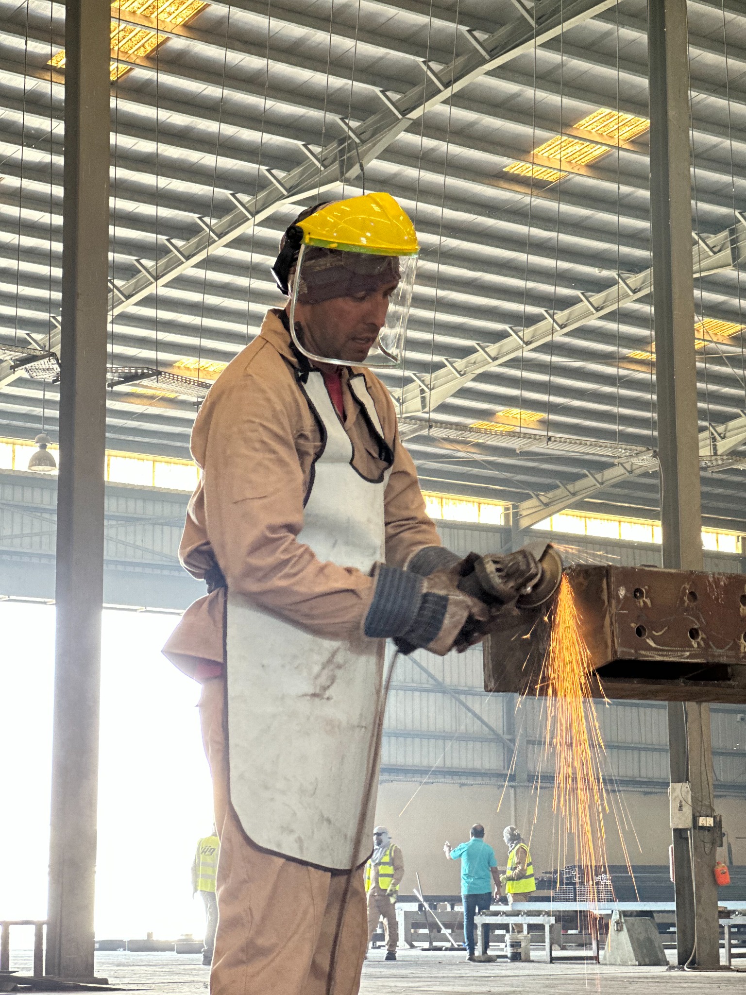 Worker cutting a steel section with sparks visible